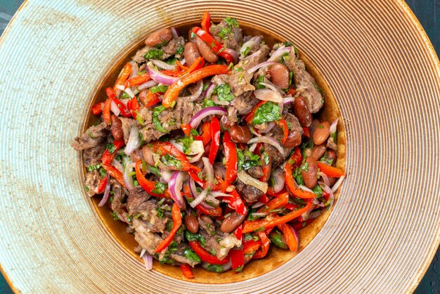 Top close view of sliced vegetable salad with meat inside plate on dark