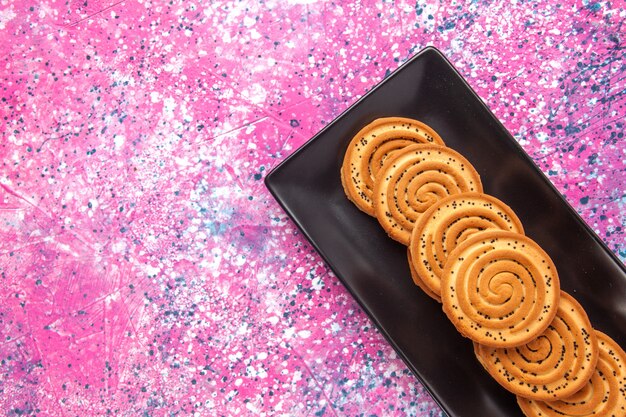 Top close view sweet cookies delicious little cookies inside black form on light pink desk.