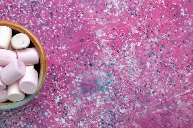 Бесплатное фото Сверху крупным планом сладкий вкусный зефир, маленький сформированный внутри круглого горшка на розовом столе.