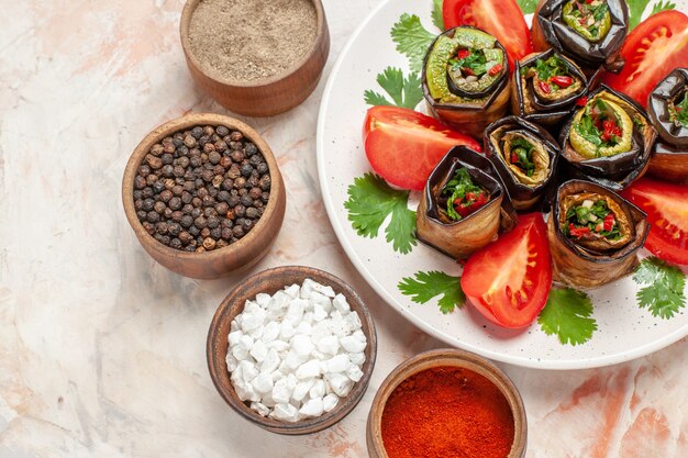 Top close view tasty eggplant rolls with greens tomatoes and seasonings