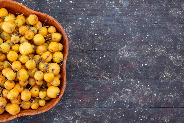 Top close view of yellow cherries sweet mellow and juicy inside plate on grey