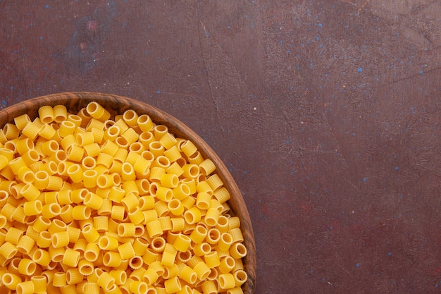 Top close view yellow italian pasta raw little formed on dark space