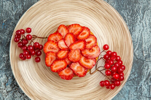 Вид сверху на вкусный клубничный торт с красными ягодами на темной поверхности