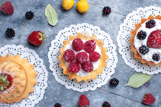 Vista dall'alto più ravvicinata di diverse torte cremose con frutti di bosco insieme a frutta fresca su luminoso