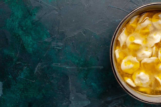 Foto gratuita zuppa di pasta vista dall'alto più vicino con carne macinata all'interno dell'impasto sulla superficie blu scuro