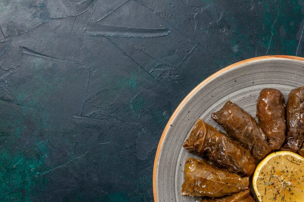 Top closer view leaf dolma delicious eastern meat meal rolled inside green leaves on dark-blue desk