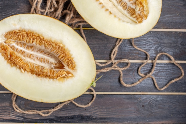 Foto gratuita vista più ravvicinata superiore melone tagliato a metà frutta dolce sullo scrittorio rustico marrone