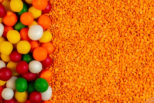 Free photo top  colorful candies on raw red lentils