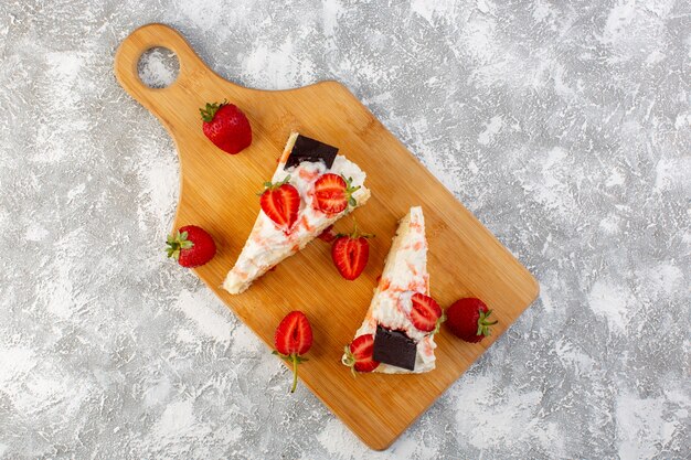 Top distant view delicious cake slices with chocolate cream and strawberry on the light background bake biscuit sugar tea sweet