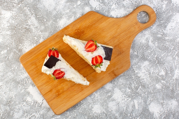 Top distant view delicious cake slices with chocolate cream and strawberry on the light background cake biscuit sugar tea sweet