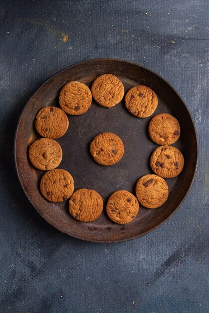 Top distant view delicious chocolate cookies inside dark round plate on the dark-grey background cookie biscuit sweet