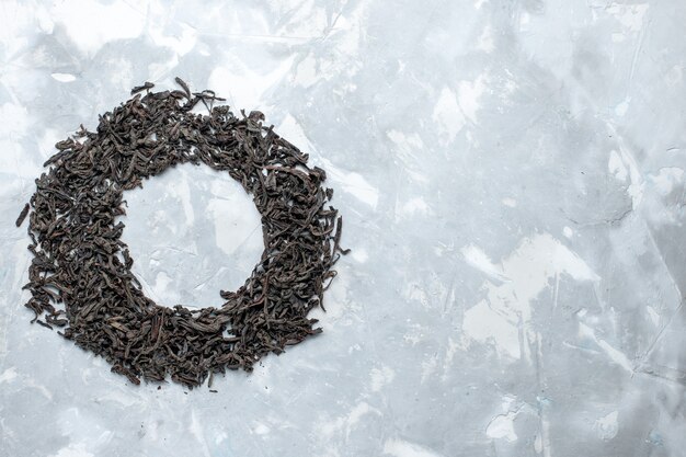 Top distant view dried tea black colored forming circle on the light table, grain tea dry color