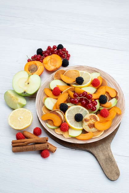 Вид сверху свежие нарезанные фрукты красочные и спелые на деревянном столе и белый фон фрукты цвет еда фото
