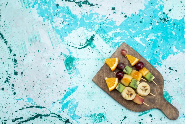 Top distant view fruit composition sliced on sticks on the bright desk fruit exotic cookie sugar