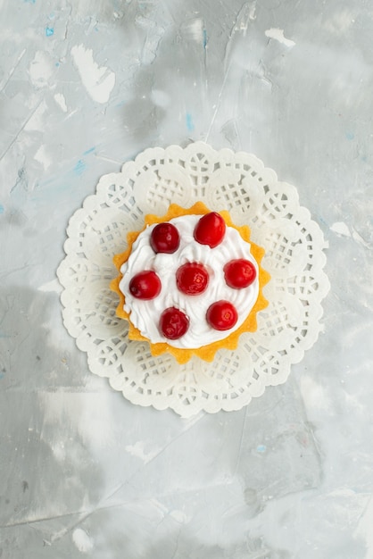 Top distant view little delicious cake with cream and red fruits isolated on the light surface  tea