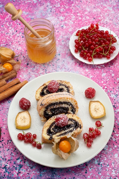 色とりどりのデスクケーキビスケット甘い果物の上に蜂蜜と白いプレート内のさまざまな果物とトップ遠景ロールケーキスライス