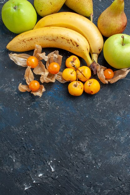 Top distant view yellow bananas pair of berries with green apples pears on dark-blue, fruit berry fresh health vitamine sweet pulp