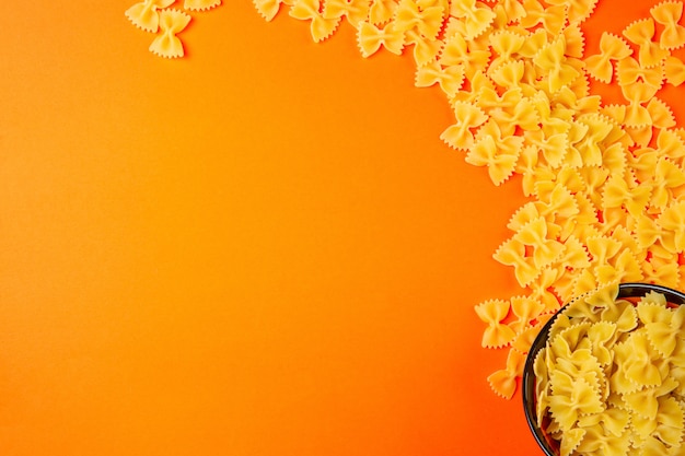 Free photo top  dry pasta farfalle with copy space on orange