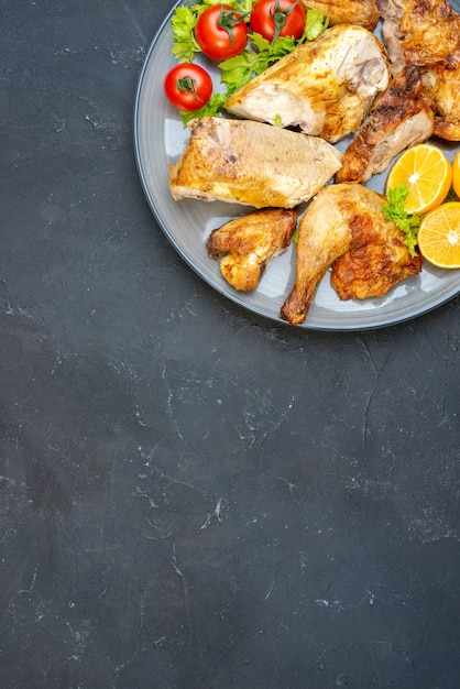 Верхняя половина вида запеченная курица, свежие помидоры, ломтики лимона на тарелке