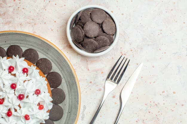 Top half view cake with pastry cream on oval plate chocolate in bowl fork and dinner knife