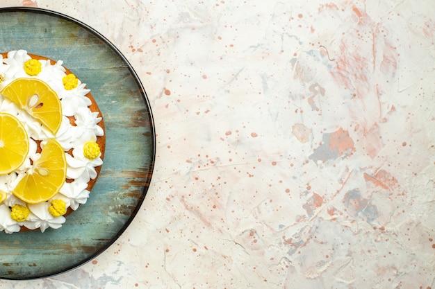 Torta a metà vista dall'alto con crema pasticcera bianca e fette di limone su piatto rotondo