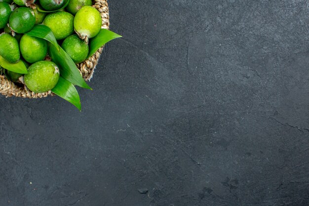 Top half view fresh feijoas in basket on dark surface free space