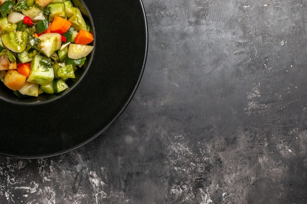 Top half view green tomato salad on oval plate on dark background