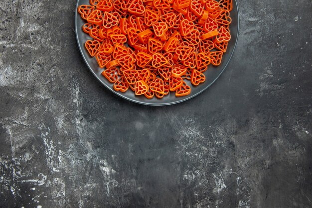 Top half view heart shaped italian pasta on black oval plate