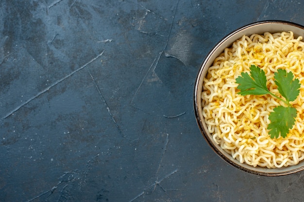 Top half view ramen noodles with coriander in bowl on dark background