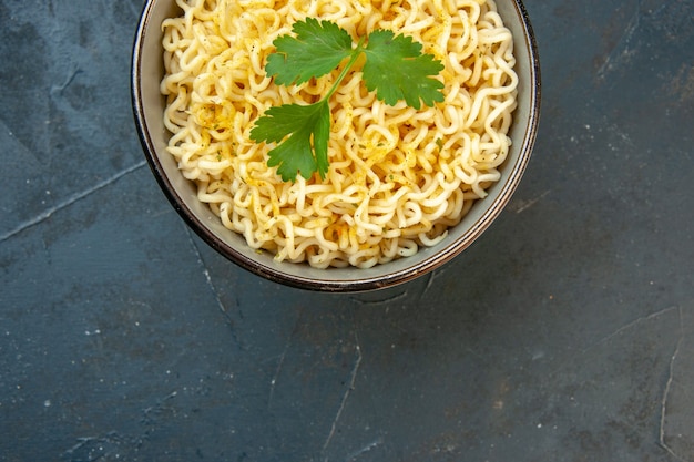 Top half view ramen noodles with coriander in bowl on dark table