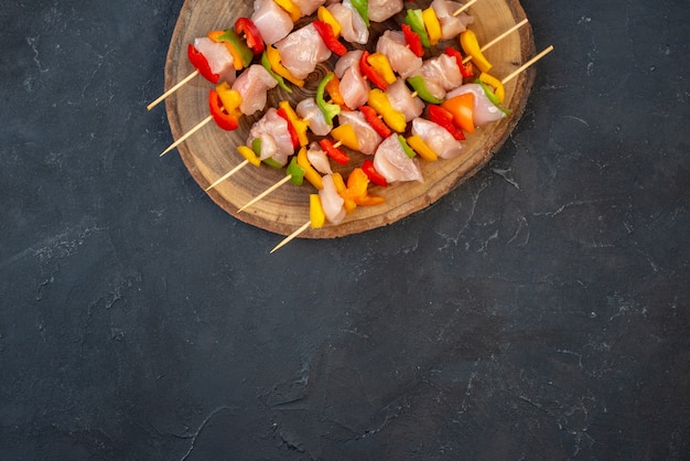 Top half view raw chicken skewer on wooden board on table