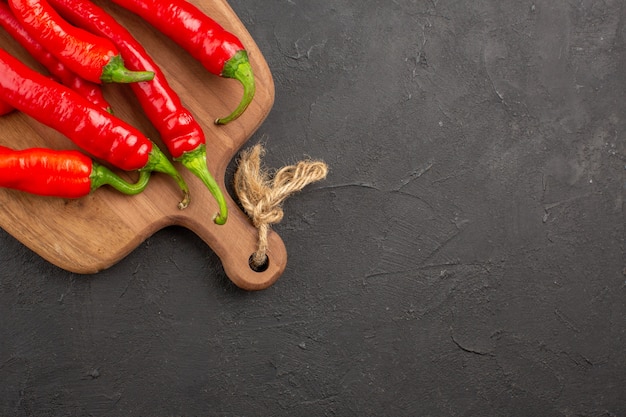 Free photo top half view red hot peppers on a chopping board on the black table