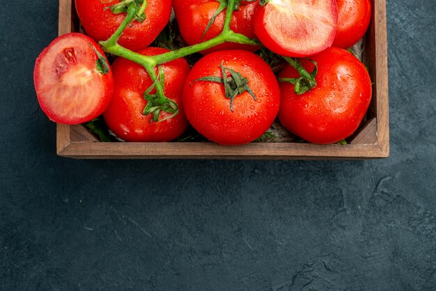 위쪽 절반 보기 빨간 토마토는 검은색 테이블 여유 공간에 있는 나무 상자에 토마토를 자른다