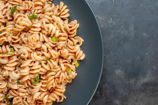 Top half view rotini pasta on round plate on dark surface