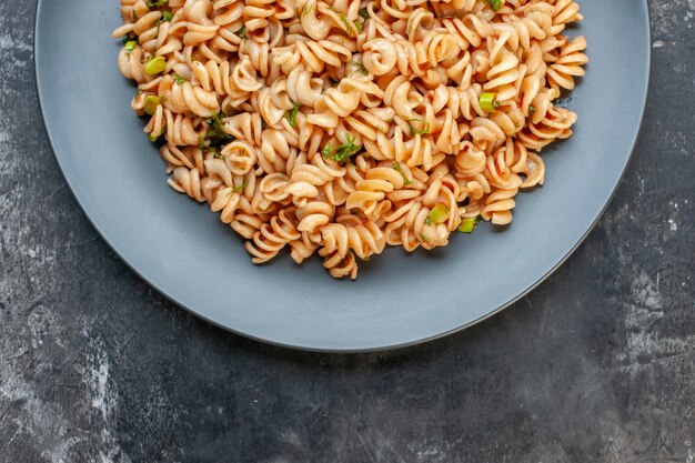 Top half view rotini pasta on round plate on dark table