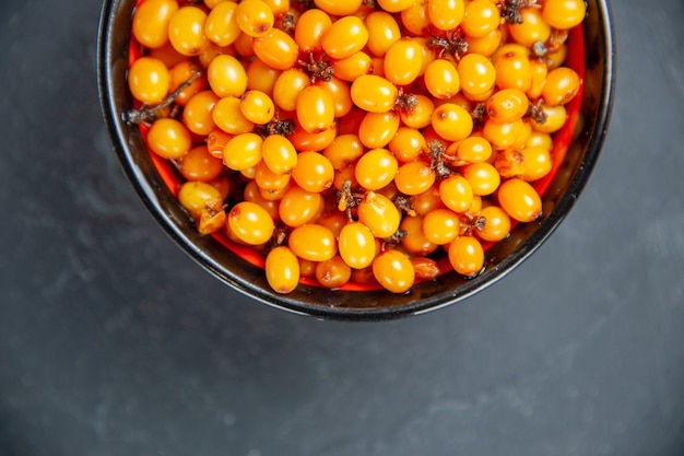 Free photo top half view sea buckthorn in bowl on dark red surface