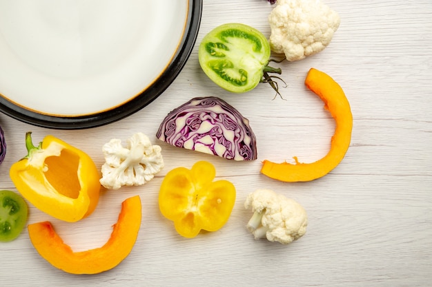 Verdure tagliate del piatto bianco di metà superiore di vista sulla superficie bianca