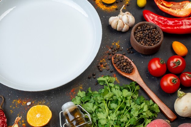 Top half view white round plate black pepper in small bowl bottle coriander garlic on table