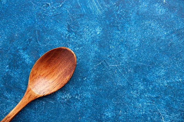 Top half view wooden spoon on blue table with copy space