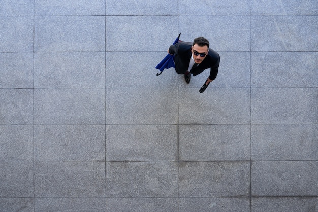 Top shot of businessman in suit and sunglasses standing on pavement