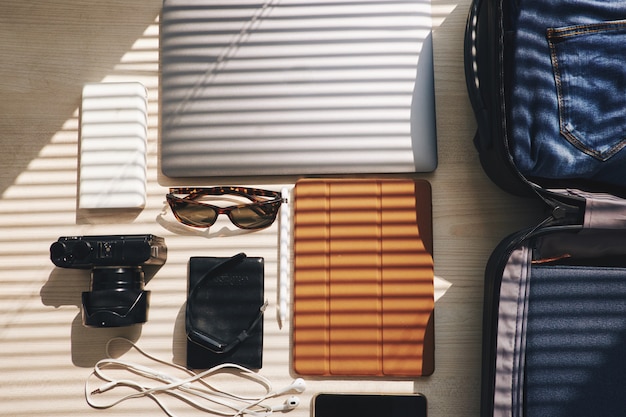 Top shot of electronic devices and suitcase lying on table, ready for business trip