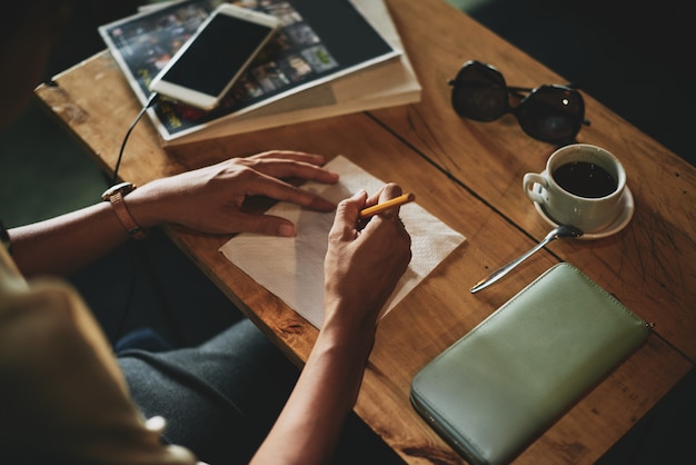 Top shot of female hands drawing on napkin in cafe