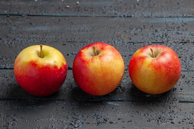 무료 사진 회색 나무 탁자에 있는 노란색-붉은 사과 3개