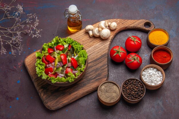 Top side view food on the board salad with tomatoes green peppers and lettuce oil and different spices