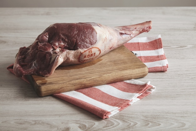 Top side view on icelandic raw lamb leg isolated on striped towel and wooden board.