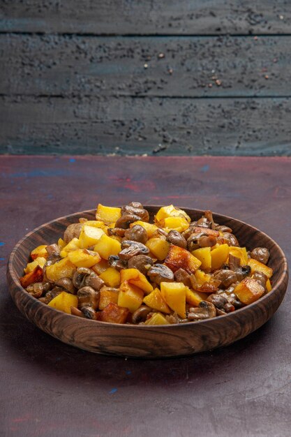 Top side view mushrooms and fried potatoes mushrooms with potatoes in a bowl on the dark surface