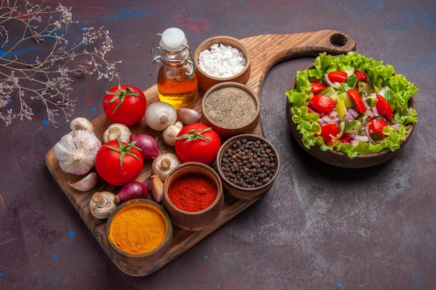 Top side view salad and spices different spices tomatoes onions mushrooms and oil on the cutting board and salad with vegetables