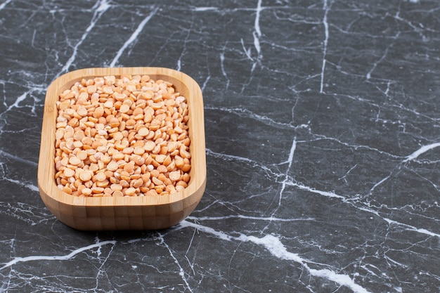 Vista superiore di piselli secchi in una ciotola di legno su pietra nera.