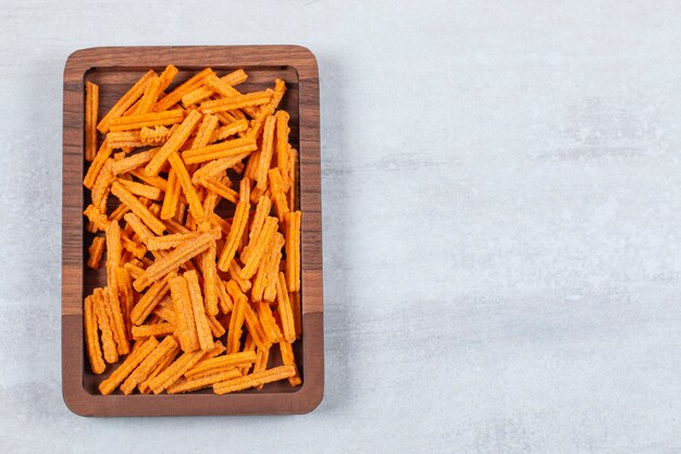 Top up view of fries on wooden plate.