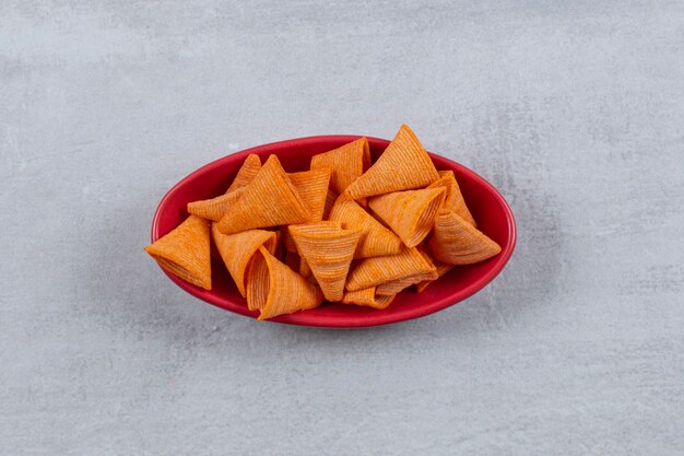 Top up view of spicy chips in red bowl.